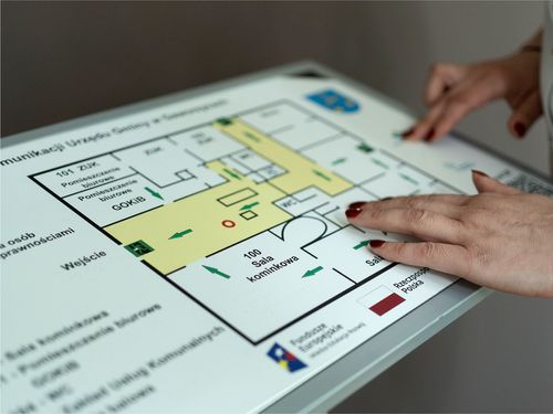 Dłonie kobiety dotykają planu tyflograficznego