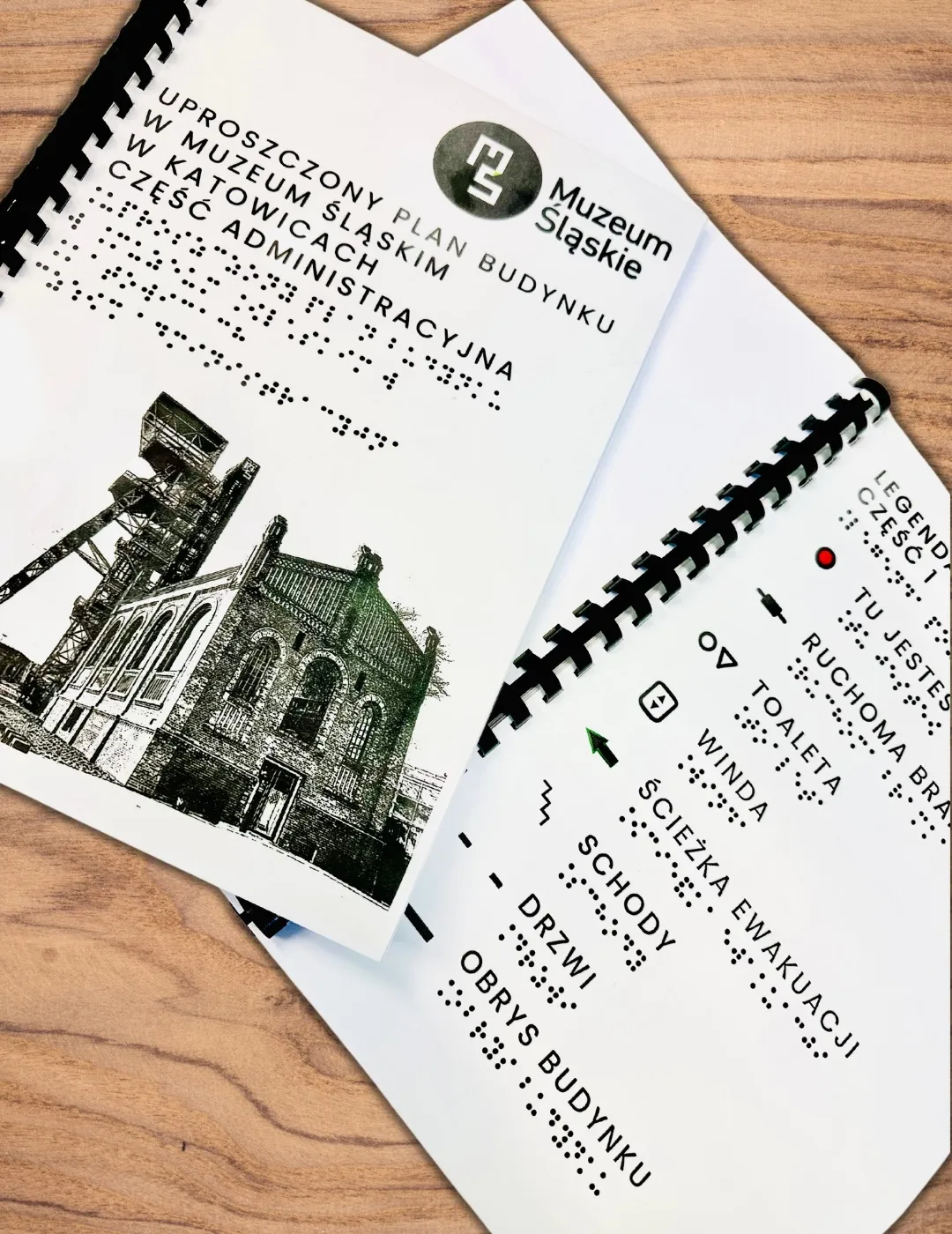 Uproszczony, dotykowy plany Muzeum Śląskiego leży na drewnianej podłodze.