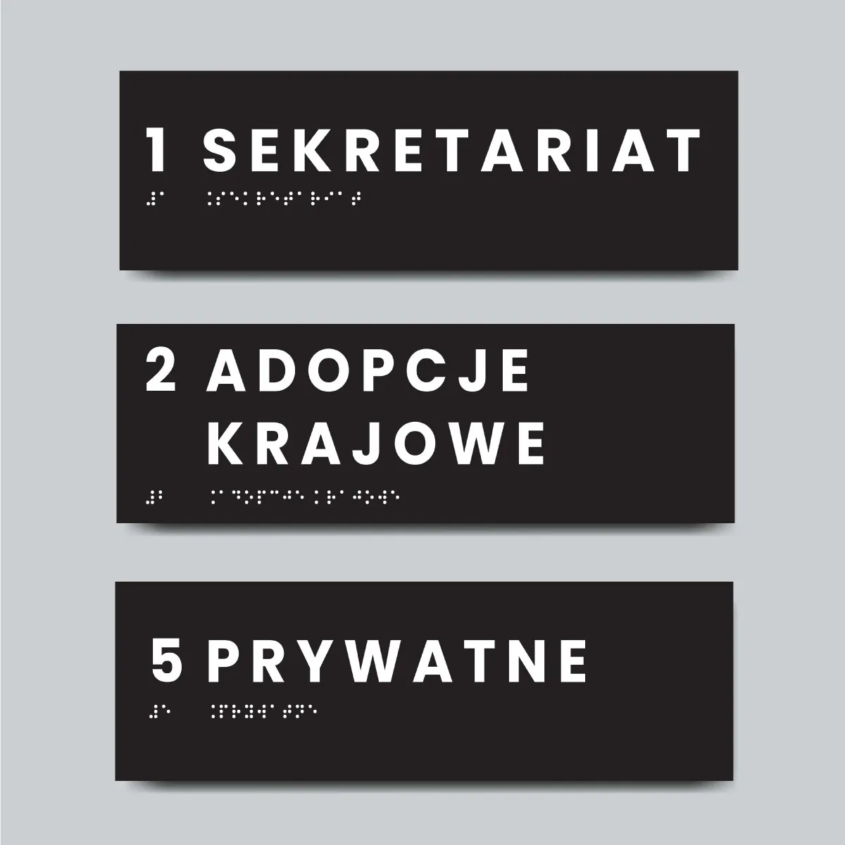 Trzy czarne tabliczki z opisem w alfabecie Braille’a